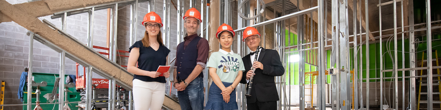 two faculty and two students in the new 91̽ performance hall during its construction